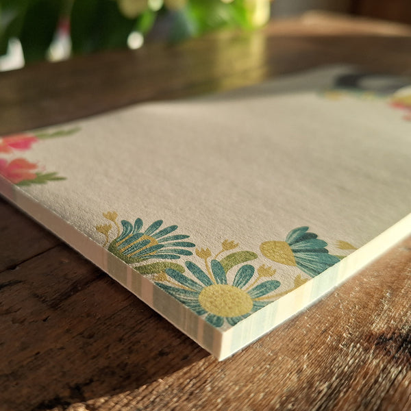 A close up view of a Hounds of Love notepad, highlighting the floral design at the top, glued edge of the pad