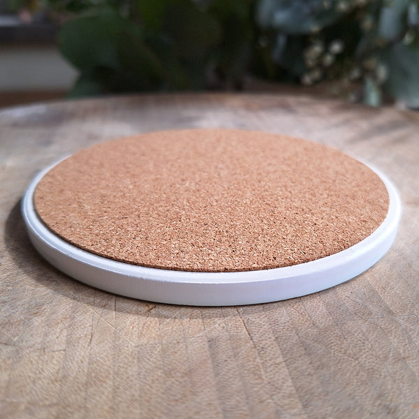 The back of a ceramic coaster showing the cork base and thickness of the item.