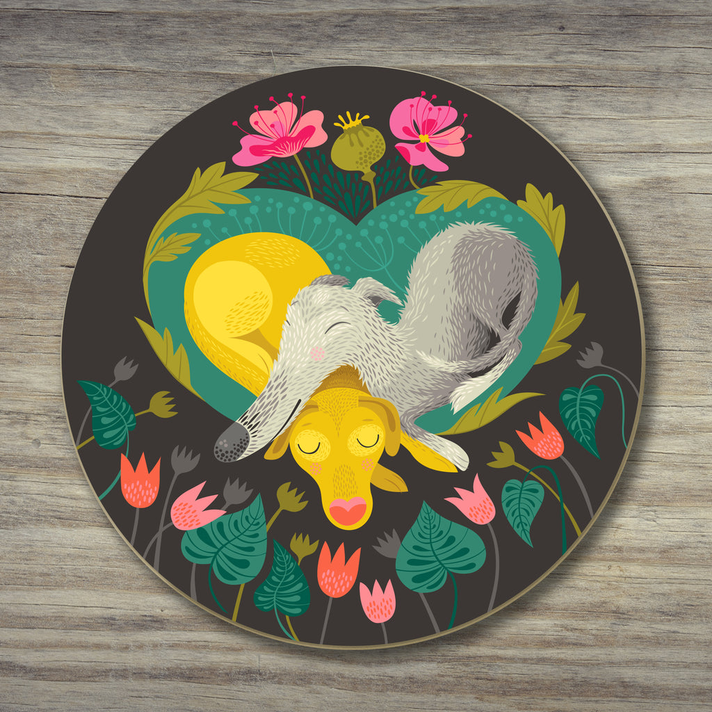 A Pops & Bumble coaster by Rollerdog, showing an illustrated lurcher and a labrador snuggling, surrounded by flowers