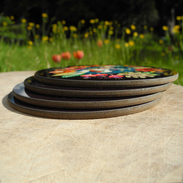 A stack of 4 Rollerdog Flower Bed coasters, photographed outside amongst flowers