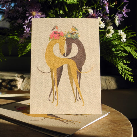 Hounds of Love postcards by Rolelrdog, shown on a table with a bunch of flowers in the background