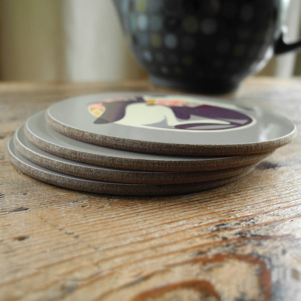 A stack of 4 Rollerdog coasters on a wooden surface