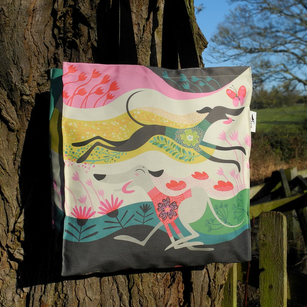 A Zoomies tote bag by Rollerdog, shown outside next to a tree