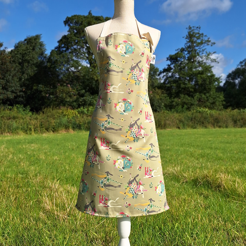 The front view of a stone-coloured Bloomin' Hounds apron by Rollerdog, photographed in a countryside setting.