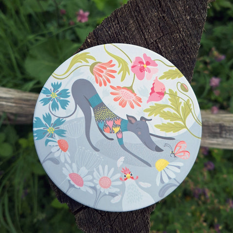 A reduced price 'Greta' ceramic coaster by Rollerdog, photgraphed on a wooden post in the countryside