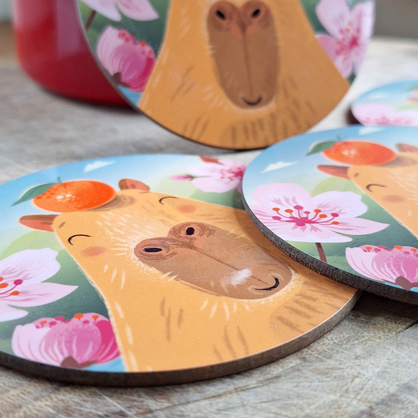 A close up view of a set of capybara coasters on a wooden surface