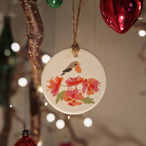 A ceramic decoration featuring a robin, hanging on a twiggy Christmas tree with fairy lights