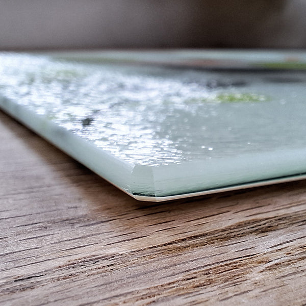 Close up view of the corner of a Rollerdog glass chopping board, showing the thickness and texture of the glass