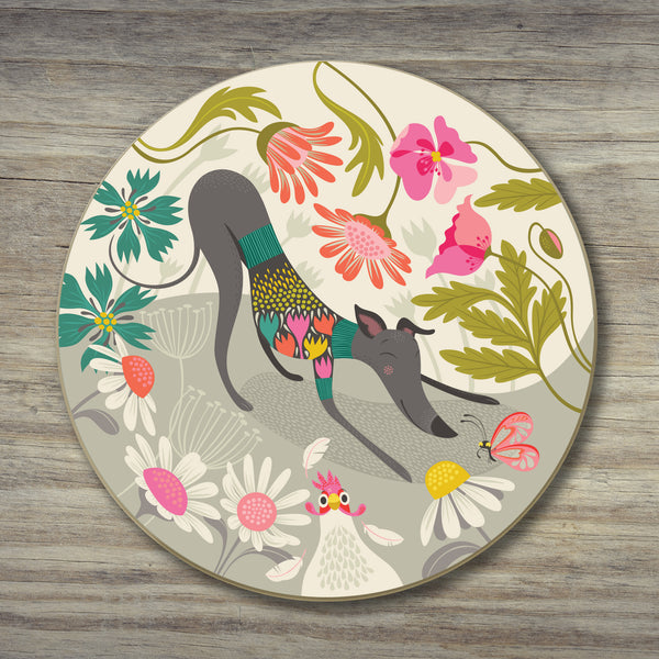 Greta Greyhound coaster by Rollerdog, showing an iillustrated greyhound bowing playfully and a chicken running away, surrounded by flowers