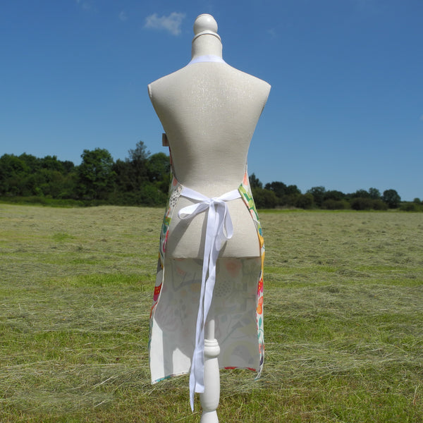 The back view of a Bright Birds apron by Rollerdog, displayed on a mannequin in the countryside