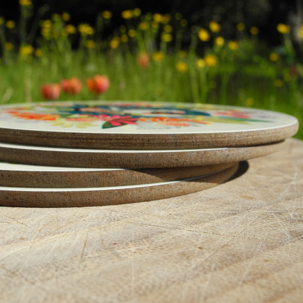 A stack of 4 Rollerdog Flower Bed coasters, photographed outside amongst flowers