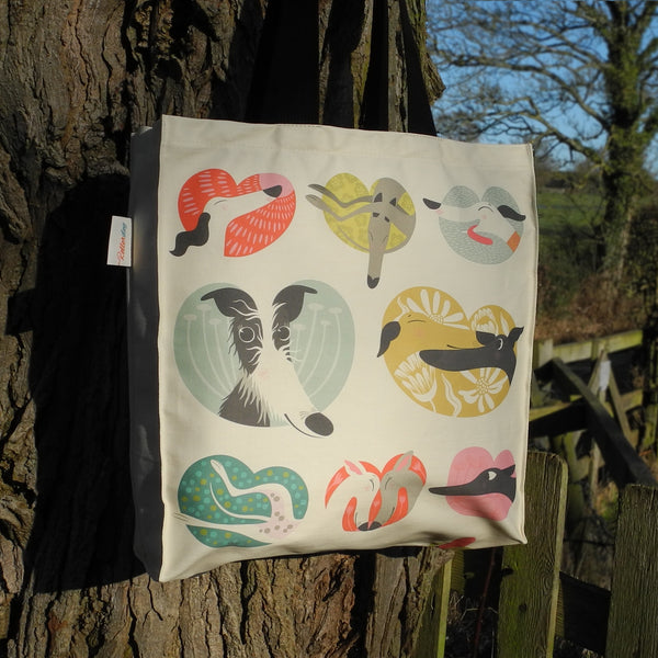 The back view of a Noses & Poses tote bag by Rollerdog, next to a tree in the countryside