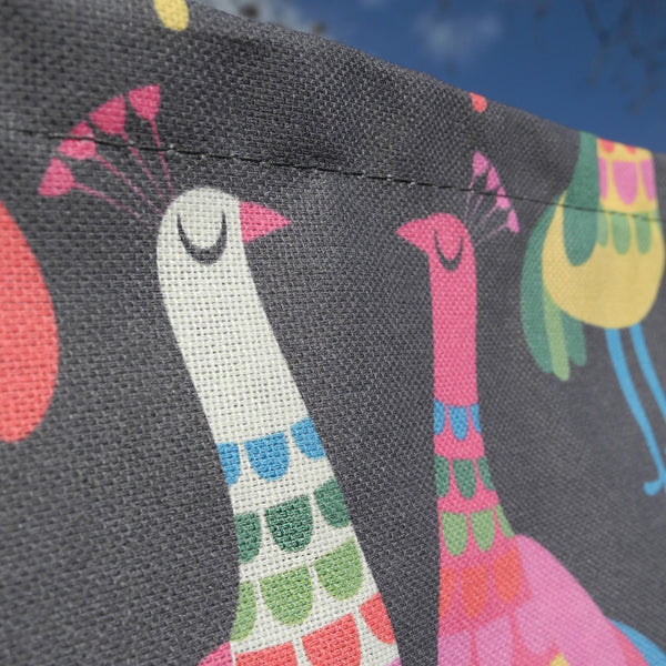 A close-up view of a Haughty Peacocks tea towel, showing the weave of the fabric