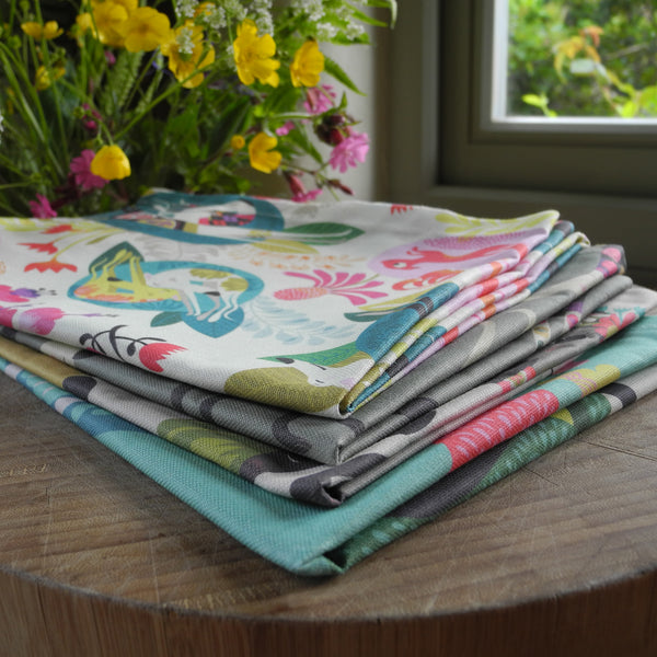 A stack of Rollerdog tea towels, with flowers in the background