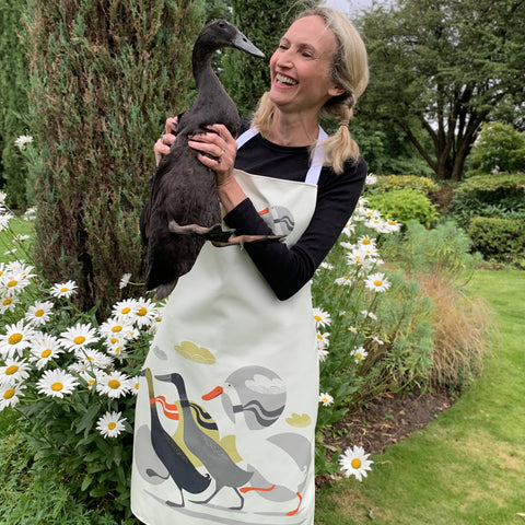 Three Ducks from Derbyshire apron, being worn by model Jen, who is holding Bakewell, one of the ducks featured on the apron