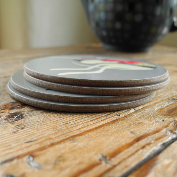 A stack of 4 Rollerdog coasters on a wooden surface